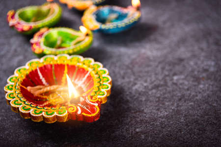 Close up of clay lit light a fire already on Diya or oil lamp, studio shot on concrete background, Decoration of Hinduism rangoli, Happy celebration Deepavali or Diwali festival conceptの写真素材