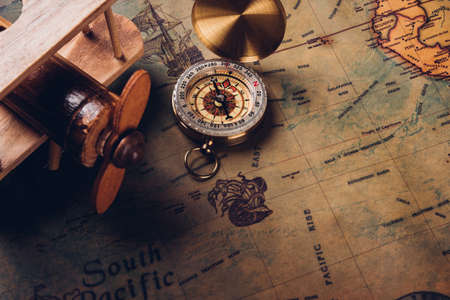 Old compass discovery and wooden plane on vintage paper antique world map background, Retro style cartography travel geography navigationの写真素材