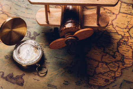 Old compass discovery and wooden plane on vintage paper antique world map background, Retro style...