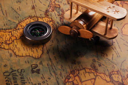 Old compass discovery and wooden plane on vintage paper antique world map background, Retro style...
