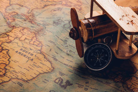 Old compass discovery and wooden plane on vintage paper antique world map background, Retro style...