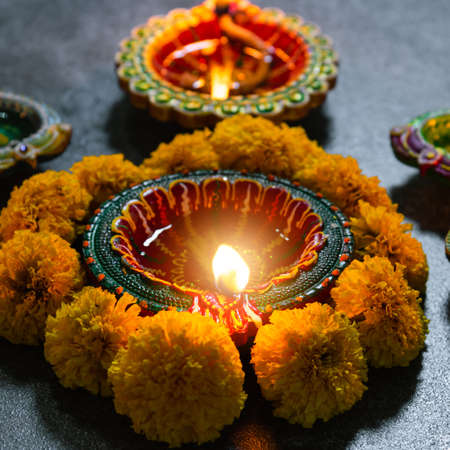 Close up clay lit light a fire already on Diya or oil lamp with flowers, studio shot on concrete...
