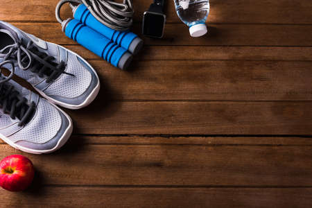 Top view of pair sports shoes, bottle water, apple and jump rope on wood table, Gray sneakers and accessories equipment in fitness GYM, Healthy workout active lifestyle diet conceptの写真素材