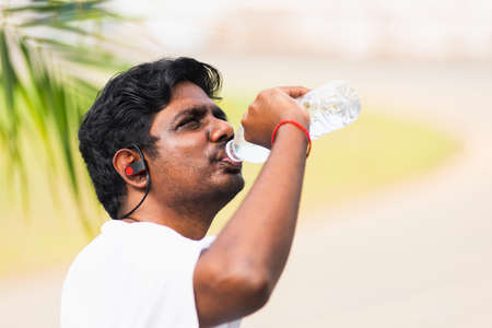 Close up Asian young sport runner black man wear athlete headphones he drinking water from a bottle...