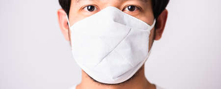Closeup Asian handsome Man wearing surgical hygienic protective cloth face mask against coronavirus, studio shot isolated white background, COVID-19 medical conceptの写真素材