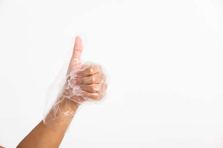 Woman hand wearing single use protect disposable transparent plastic glove with thumb up gesture, studio shot isolated on white backgroundの写真素材