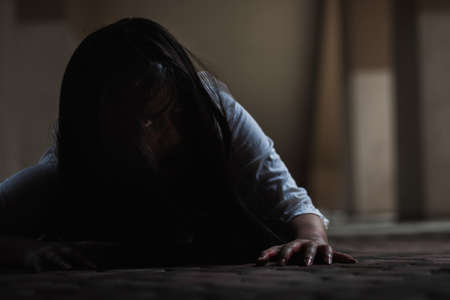 Female zombie in blood. Asian Woman ghost with blood. Horror scary fear in dark house creepy crawling move slowly creeping out. Hair covering face her eye looking camera, Halloween festival conceptの写真素材