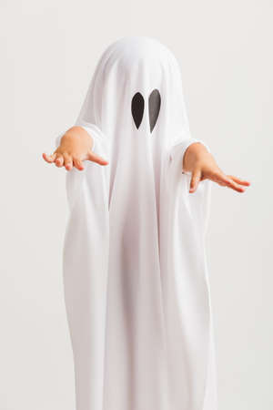 Funny Halloween Kid Concept, little cute child with white dressed costume halloween ghost scary, studio shot isolated on white backgroundの写真素材