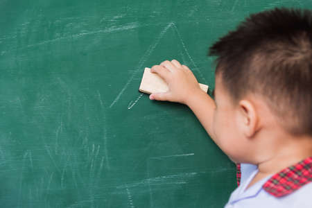 Back to School. Back of Asian cute little child boy kindergarten preschool in student uniform wiping...
