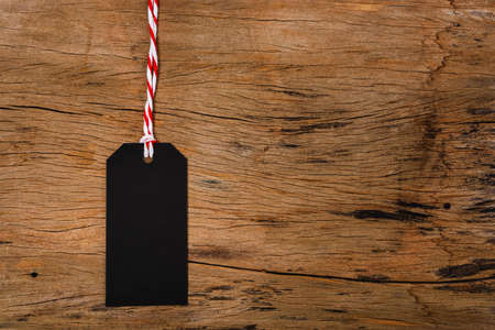 Blank black tag on wooden background, for use your text