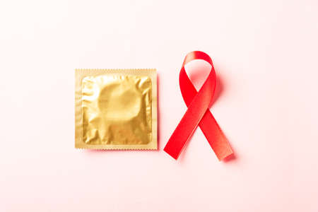 Red bow ribbon symbol HIV, AIDS cancer awareness and condom with shadows, studio shot isolated on pink background, Healthcare medicine sexually concept, World AIDS Dayの写真素材