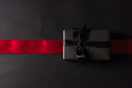 Black Friday Sale concept, Top view of gift box wrapped black paper and black bow ribbon press,...