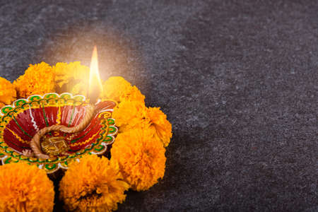 Top view overhead clay lit Diya or oil lamp and yellow flower, studio shot on concrete background, Decoration of Hinduism rangoli, Happy Deepavali or Diwali festival conceptの写真素材
