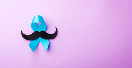 Black mustache paper and light blue ribbon, studio shot isolated on purple background, Prostate cancer awareness month, Fathers day, minimal November moustache conceptの写真素材