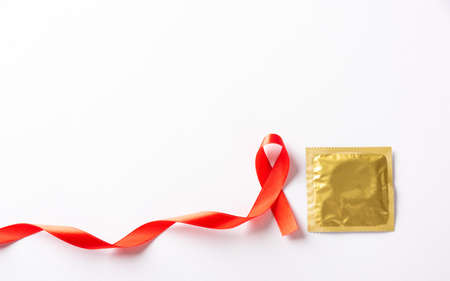 Red bow ribbon symbol HIV, AIDS cancer awareness and condom with shadows, studio shot isolated on...