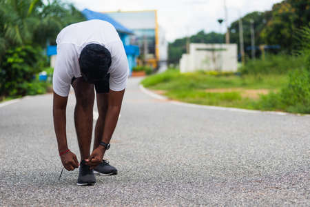 Close up Asian sport runner black man standing he trying shoelace running shoes getting ready for...