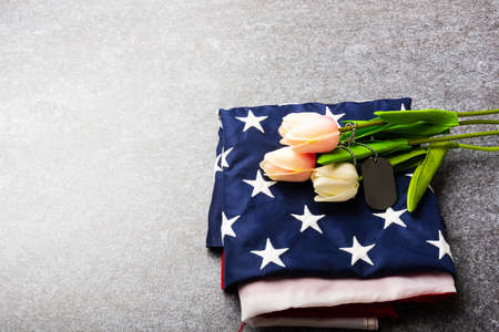 Traditional folded of America United States flag, tag and tulip flower, memorial remembrance and thank you of hero, studio shot with copy space concrete board background, USA Veterans day conceptの写真素材