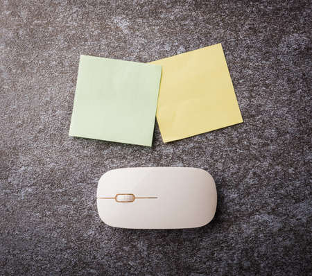 Above office table desk with blank paper stick note yellow and green and with computer mouse on...