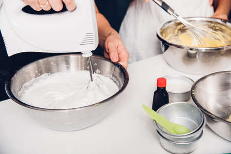 Woman cooking whisk dough mixer in bowl by machine at homemade