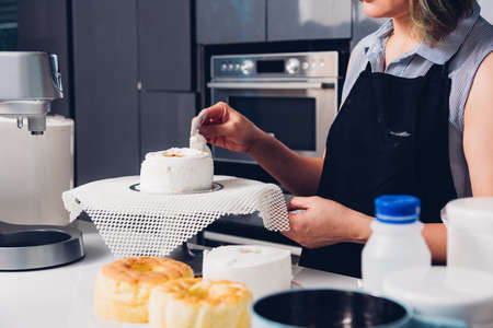 Woman during decorating cake with cream at homemade