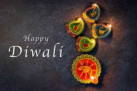 Close up of clay lit light a fire already on Diya or oil lamp, studio shot on concrete background,...