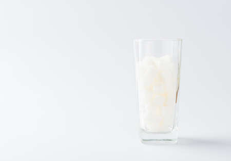 A glass full of white sugar cube sweet food ingredient, studio shot isolated on white background, health high blood risk of diabetes and calorie intake concept and unhealthy drinkの写真素材