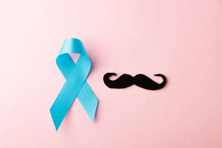 Black mustache paper and light blue ribbon, studio shot isolated on pink background, Prostate cancer awareness month, Fathers day, minimal November moustache conceptの写真素材