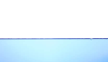 Light blue water wave with air bubbles and a little bit splashed underwater, studio shot isolated on white background. The abstract clean surface on liquidの写真素材