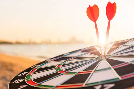 Dart arrow hit to center on bullseye(bull's-eye) of a dartboard is a target of purpose challenge business at sunset, expert strategy market target, objective financial and goal a conceptの写真素材