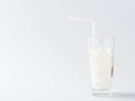 A glass full of white sugar cube sweet food ingredient, studio shot isolated on white background, health high blood risk of diabetes and calorie intake concept and unhealthy drinkの写真素材