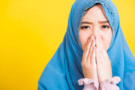 Asian Muslim Arab, Portrait of happy beautiful young woman religious wear veil hijab she sad crying using hand wiping tears in her eyes, studio shot isolated on yellow background with copy spaceの写真素材