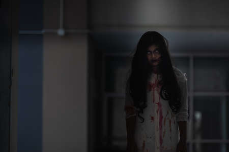 Horror evil woman ghost creepy in a dark room at house. The female devil is scary she haunted at the abandoned building, Happy Halloween day concept