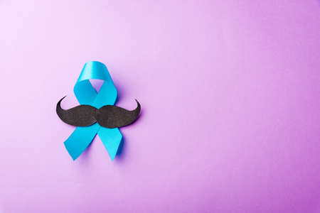 Black mustache paper and light blue ribbon, studio shot isolated on purple background, Prostate cancer awareness month, Fathers day, minimal November moustache conceptの写真素材