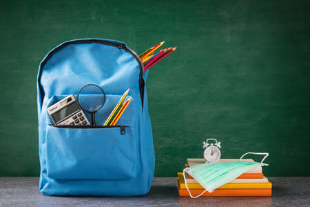 Front school backpack and accessories with face mask protect on table at chalkboard, student bag supplies at classroom backboard, Back to school education new normal outbreak COVID-19 or coronavirusの写真素材