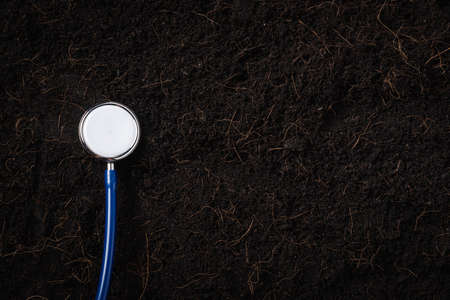 Black land for plant background and doctor stethoscope, Top view of Handprint on fresh soil with...