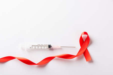 Red bow ribbon symbol HIV, AIDS cancer awareness and syringe with shadows, studio shot isolated on...