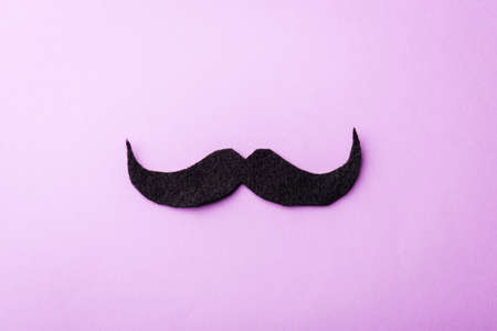 Black mustache paper, studio shot isolated on purple background, Prostate cancer awareness month, Fathers day, minimal November moustache conceptの写真素材