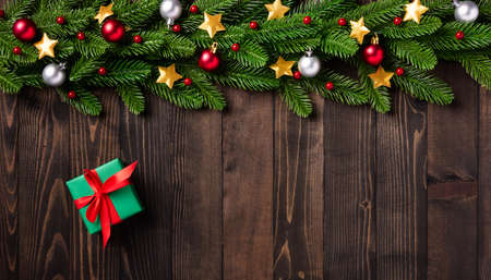 Christmas holiday garland border, Top view of tree fir branches, and Xmas stars ornament bauble decor and gift box on black table wood background with copy spaceの写真素材