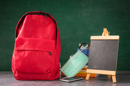 Front school backpack and accessories with face mask protect on table at chalkboard, student bag supplies at classroom backboard, Back to school education new normal outbreak COVID-19 or coronavirusの写真素材