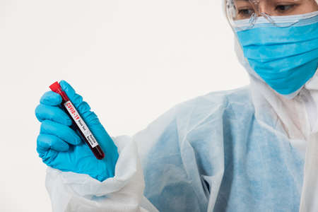 Medical scientist in PPE uniform wear a mask holding test tube Coronavirus test blood sample in a hospital laboratory for analyzing isolated on white, medicine COVID-19 pandemic outbreak conceptの写真素材