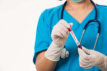 Nurse in blue uniform wear a mask holding test tube sample Coronavirus test blood in the laboratory for analyzing isolated on white background, medicine COVID-19 pandemic outbreak conceptの写真素材