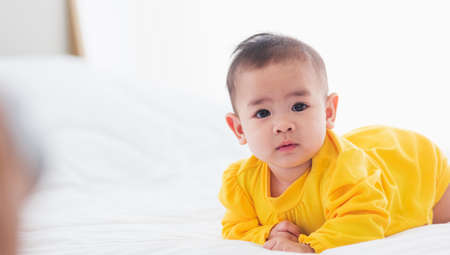 Portrait of beautiful young Asian newborn little baby prone on the bed at home, Happy baby smile...