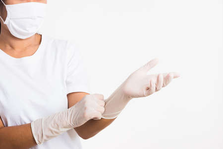 Woman wearing and putting hand to white rubber latex surgical medical glove for doctor and fave mask protect, studio shot isolated on white background, Hospital medical infection control conceptの写真素材
