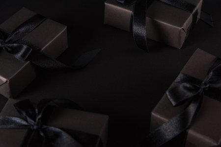 Black Friday sale shopping concept, Top view of gift box wrapped black paper and black bow ribbon present around free copy space for text, studio shot on dark backgroundの写真素材