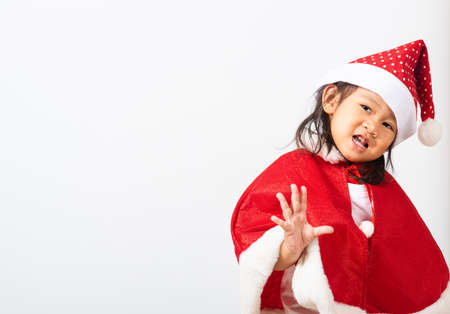 Portrait of Asian little cute girl smiling, Kid dressed in Santa Claus hat the concept of holiday Christmas Xmas day or Happy new year, studio shot isolated on white background with copy space for textの写真素材