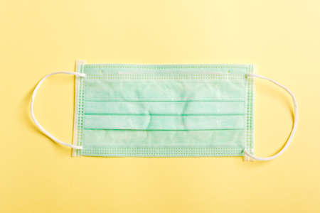 Medical blue protective face mask for cover mouth and nose, studio shot isolated on yellow...