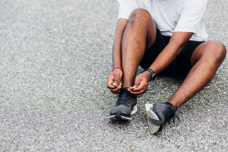 Close up Asian sport runner black man wear watch sitting he trying shoelace running shoes getting ready for jogging and run outdoor street health park with copy space, healthy exercise workout conceptの写真素材