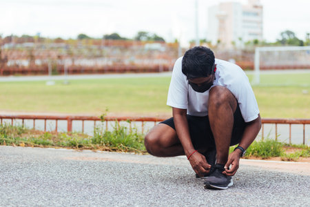 Close up Asian sport runner black man wear watch sitting he trying shoelace running shoes getting...