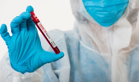 Medical scientist in PPE uniform wear a mask holding test tube Coronavirus test blood sample in a...