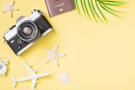Flat lay top view mockup retro camera films, airplane, passport, starfish traveler tropical beach accessories on a yellow background with copy space, Vacation summer travel and business trip conceptの写真素材